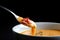 Extreme close-up of a spoon scooping up a creamy, lobster bisque soup from a white porcelain bowl