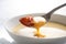 Extreme close-up of a spoon scooping up a creamy, lobster bisque soup from a white porcelain bowl