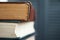 Extreme close-up of a stack of old books, yellowed pages, a broken back of a book against a gray bookcase, soft focus