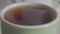 Extreme close-up of sugar falling into cup of black tea. Unknown person adding crystalline organic glucose to the drink