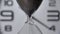 Extreme close up of a transparent hourglass with flowing black sand on blur dial background. Old classic timer. Time