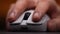 Extreme close-up of unrecognizable man using modern wireless mouse working on computer. Close-up of male finger clicking