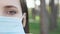 Extreme close up of woman face puts on protective medical face mask for virus infection prevention and protection. Young female in