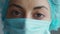 Extreme closeup face and eyes woman doctor or nurse wearing medical cap and face mask