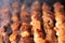 Extreme closeup shot of meat on skewers on a grill, with smoke