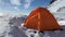 An extreme expeditionary orange tent stands in the wild wind. Travel to the Kamchatka Peninsula.