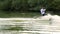 Extreme happy businessman in a suit with a tie and sunglasses rides on wakeboard on a lake