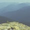 Extreme hikes. Huge stones overgrown with green ome stoch against the backdrop of high mountain ranges in the fog