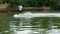 Extreme man in a suit with a tie and sunglasses rides on wakeboard and jumping on a springboard on a lake