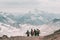 Extreme recreation and mountain tourism. A group of hikers down the mountain path over the horizon. In the background, large snow-