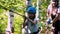 Extreme rope adventure in the park - young family of little girl and her mother crossing the rope bridge