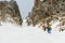 Extreme skiers climb to the top along the couloir between the rocks before the descent of the freeride backcountry