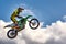 Extreme sports background - silhouette of biker jumping on motorbike on sunset, against the blue sky with clouds