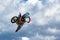 Extreme sports background - silhouette of biker jumping on motorbike on sunset, against the blue sky with clouds