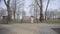 Extreme wide shot of lonely little girl sitting on bench in park. Caucasian child with long curly hair get lost in