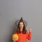 Extremely amazed winsome woman dressed in witch hat holding orange pumpkin isolated on gray background, pointing finger up at copy
