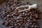 Extremely close-up of coffee beans spilling out of wooden scoop on wooden table, selective ficus