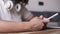 Extremely close of a young girl in white shirt sitting by the table with headphones on her neck. Mobile phone in hands