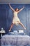 Extremely excited woman in nightgown jumping on bed with arms an