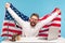 Extremely happy businessman raising American flag and yelling crazy for joy in office workplace, celebrating labor day