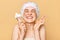 Extremely happy hopeful woman wearing shower cap holding makeup brushes keeps eyes closed crossing fingers making wish hopes for