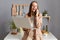 Extremely happy woman with brown hair wearing formal suit posing in kitchen, working from hone on notebook , having break, talking