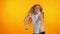 Extremely joyful teen girl dancing on orange background, celebrating achievement