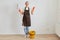 Extremely satisfied woman wearing orange rubber gloves, brown apron and jeans washing floor at home, holding mop and clenched