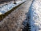 Extremely slippery footpath covered with melting snow and visible frozen ice footprints after heavy snowing in city in winter.