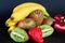 Exxposition of fresh organic kiwi, strawberry, banana and half of garnet on black baground, fresh fruit, food for good morning.