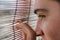 Eye close up. Young guy looking through the blinds. An aspiring look. Close-up face of a man next to wooden shutters