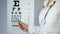 Eye doctor pointing at medical table with letters, examining patients eyesight