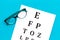 Eye examination. Eyesight test chart and glasses on blue background top view