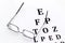 Eye examination. Eyesight test chart and glasses on white background