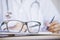 Eye glasses on desk with blur background of doctor writing prescription