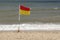 Eye-level shot of a red and yellow flag at the beach indicating a swimming area with lifeguards