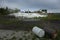 Eye-level shot of tractors in a distance with construction sand and barrels in the foreground