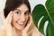 Eye Skin Care and Treatment. Portrait of beautiful young happy woman holding hands at eyes skin at green palm leaf. Girl enjoying