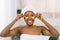 Eye skin treatment. Young African-American woman in white towel on the head with under-eye patches on light background
