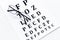 Eye test, eye examination. Glasses with transparent optical lenses on eye test chart on white background top view