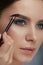 Eyebrow coloring. Woman applying brow tint with makeup brush