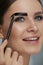 Eyebrow coloring. Woman applying brow tint with makeup brush