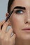 Eyebrow coloring. Woman applying brow tint with makeup brush