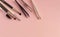 Eyebrow shaping tools, tweezers, brushes on pink background