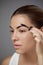 Eyebrows shaping. Portrait of beautiful girl with brow pencil. Close-up of young woman with professional makeup contouring brows w