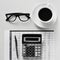 Eyeglasses, coffee and calculator on an office desk