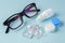 Eyeglasses and contact lenses with container on blue background