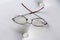 Eyeglasses with cracked lens on cream colored ottoman