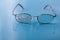 Eyeglasses with cracked lens on shiny blue background