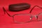 Eyeglasses and glasses case on red background